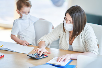 Fototapeta premium Boy and exhausted mother trying to work at home during coronavirus pandemic