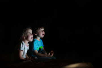 Small children in a dark room watching TV