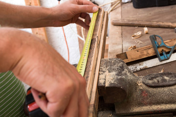 Male carpenter working on old wood in a retro vintage workshop.