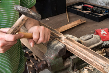 Male carpenter working on old wood in a retro vintage workshop.
