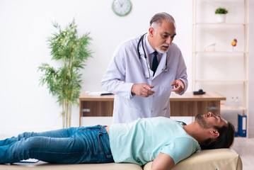 Fototapeta premium Injured young man visiting old doctor