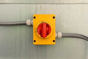 Rotating large red power switch with cables on the sides.