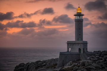 Faro de Punta Nariga con la luz encendida al atardecer en Malpica de Bergantiños en Galicia en...