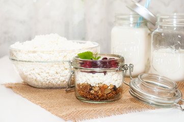 the concept of healthy and proper nutrition. Milk in a jar with a handle, cottage cheese and granola in a jar on a napkin with a mint leaf and cranberries