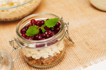 the concept of healthy and proper nutrition. Milk in a jar with a handle, cottage cheese and granola in a jar on a napkin with a mint leaf and cranberries