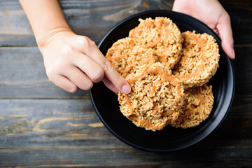 Sweet crispy rice with cane sugar drizzle on black plate eating by hand, Local Thai snack (Khao Tan), Top view