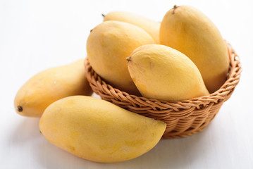 Ripe mango fruit in a basket on white table, Tropical fruit, Thai mango (Nam Dok Mai)