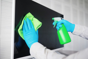House cleaning concept. Wipe dust off surfaces. Disinfectant treatment of door handles TV electrical. Sanitary treatment at home in quarantine.