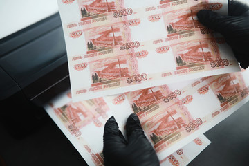 The concept of the global economic crisis. Illegal production of money, the inscription on the bill "five thousand rubles." Print money at home. Seal of five thousandth banknotes by a criminal.