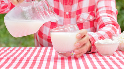 Woman pours milk from jug into glass