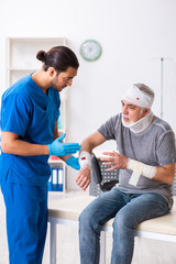 Young male doctor and old patient in first aid concept