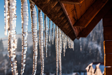 icicles hanging from the roof on a sunny day in the mountains
