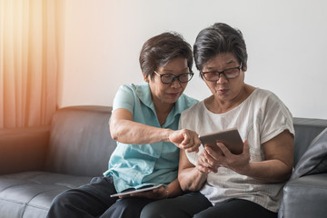 geing society concept, Asian elderly senior adult women sisters using mobile digital tablet smart...