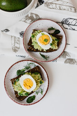 Avocado toast on black bread with seeds with egg and herbs on a plate. Guacamole
