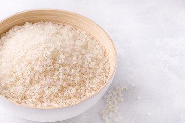 Raw uncooked rice close-up in a bowl on a white background. Copy space