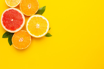 Citruses fruits on yellow background with copyspace, fruit flatlay, summer minimal compositon with grapefruit, lemon, mandarin and orange