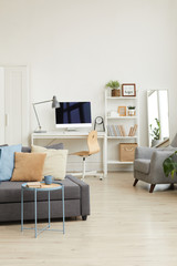 Wide angle background image of cozy apartment interior in minimal Scandinavian design and focus on grey sofa with decor elements, copy space