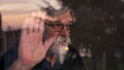 Fototapeta premium Senior man looking outside of the window. Quarantine. Pandemic. Sad.