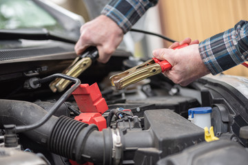 Fototapeta na wymiar Hands of car mechanic using car battery jumper cable