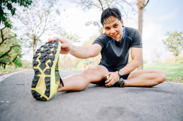 Asia man runner doing stretching exercise, warm up before for running in morning on track in the park 