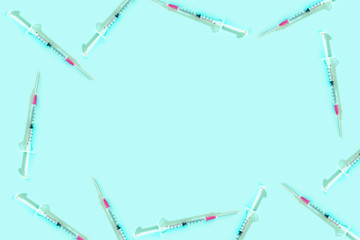 Syringes frame on blue background with copy space. Corona virus vaccine. Pandemic and cure concept