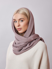 European Muslim woman with a blonde hair in a headscarf shawl dressed on her head. Beautiful girl in sweater with soft skin, natural cosmetics