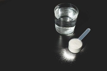A scoop of collagen powder on black background.  Flat lay, top view. Copy space for your text.