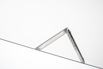 computer mouse under inverted laptop on glass table surface isolated on white background  