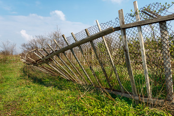 Old broken wooden fence in a green field