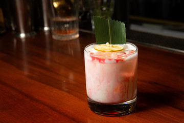 Delicious cocktail with cream in the bar on the wooden counter.
