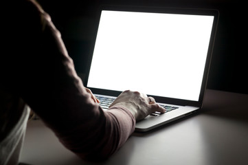 The young woman sitting in the dark living room and working with laptop