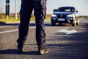 Police officer stops the car on the road.