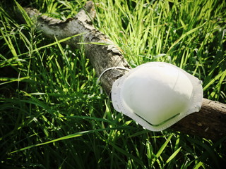 Protective mask thrown into nature on a tree trunk