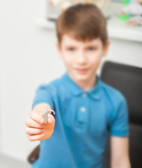 Child holding in his hand a hearing aid that will help him hear the sounds of the world. Hearing aid close-up