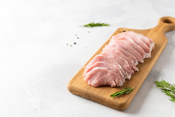 Fresh meat with spieces for cooking on wooden board on white background, side view, copy space. Cooking, raw ingredients. Butcher shop banner