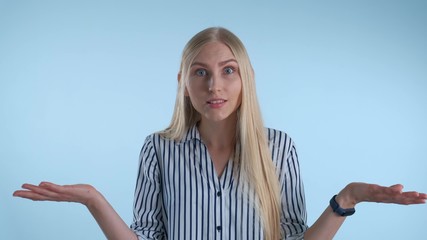 Blonde young woman misunderstanding something on blue background. She showing this emotion on face...