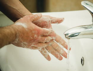 hands in soap under the tap with water close-up