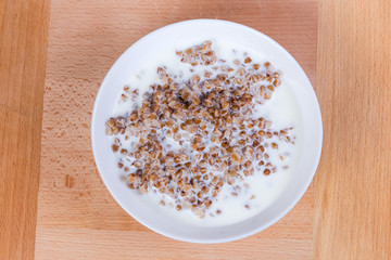 Top view of buckwheat porridge with milk in white bowl