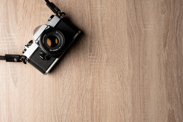 Top view of an analog retro camera on a wooden table with copy space.