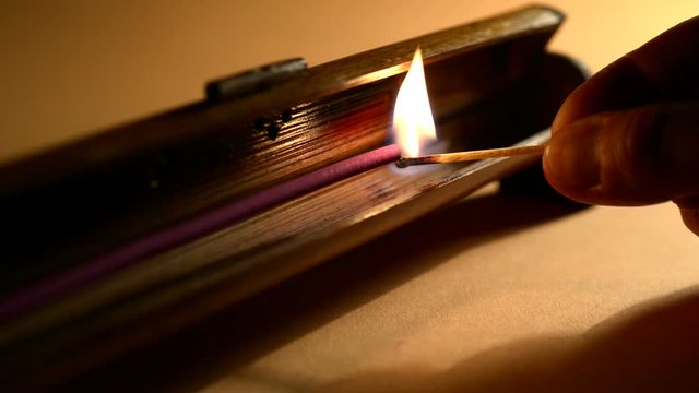 A man lights a incense stick mounted in a bamboo holder