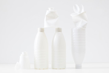 Minimal composition of white plastic bottles and items on white background, waste sorting and recycling concept