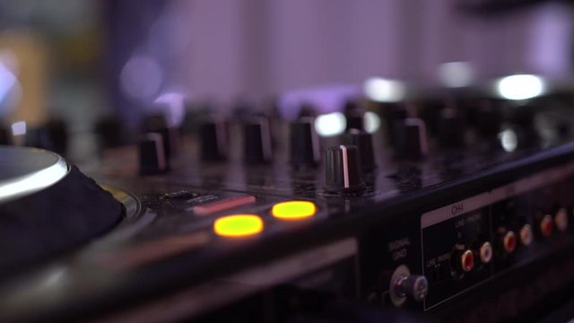 Closeup of a DJ console. DeeJay mixing table. CD players and DJ console during the party. Black Modern DJ Set Turntable Mixer Equipment with Colorful button Lights. 