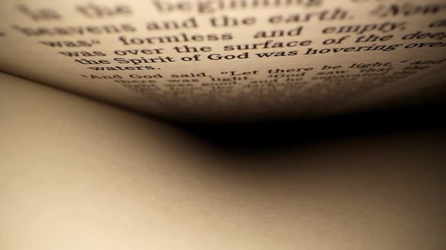 "Let there be light". Starting to move down first column of the Bible, words on top and blank page on bottom. Moving towards and past one of the iconic phrases of the of Genesis - "Let there be light"