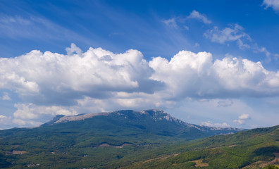Sky with clouds over mountain with slopes covered with forests