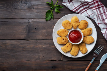 Fried chicken nuggets with tomato ketchup sauce. Wooden background. Copy space.