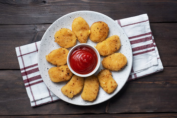 Fried chicken nuggets with tomato ketchup sauce. Wooden background. Copy space.