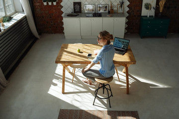 Top view woman working from home during quarantine. Sharp long shadows, bright sun. Home