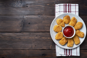 Fried chicken nuggets with tomato ketchup sauce. Wooden background. Copy space.
