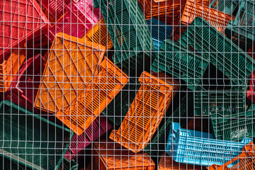 Old plastic boxes in a warehouse as a trash behind the metal mesh fence.