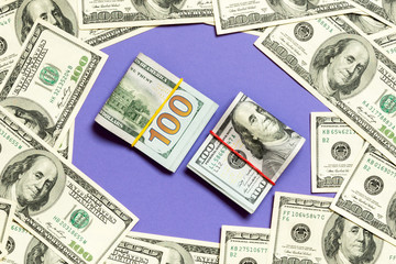 Frame of one hundred dollar bills with stack of money in the middle. Top view of business concept on purple background with copy space